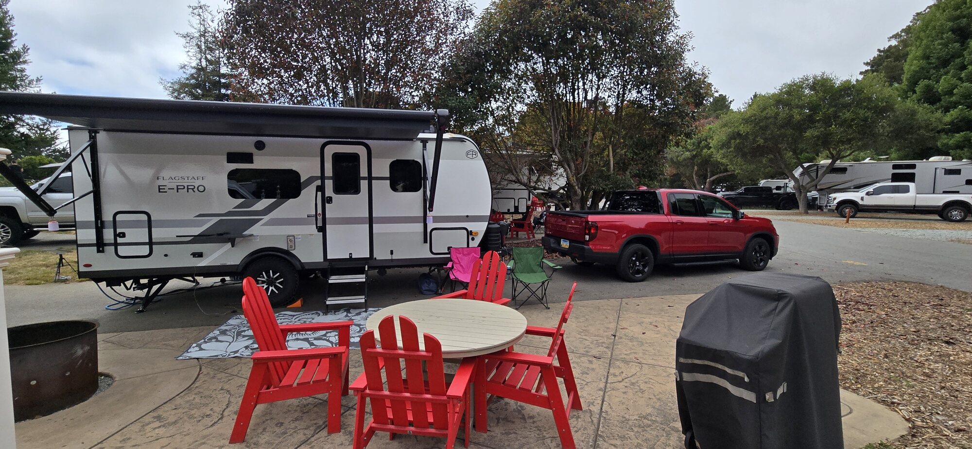 A travel trailer and red pickup set up at a campsite